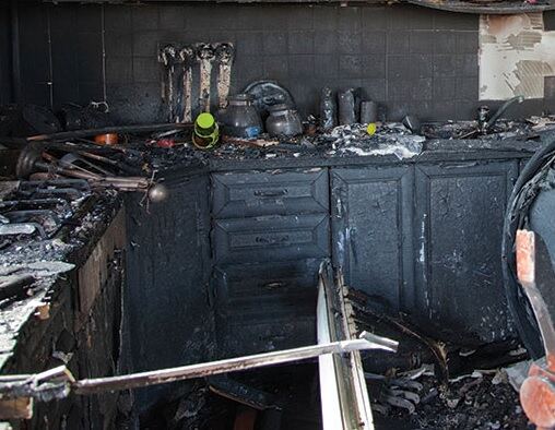Fire-damaged kitchen with heavy soot and char