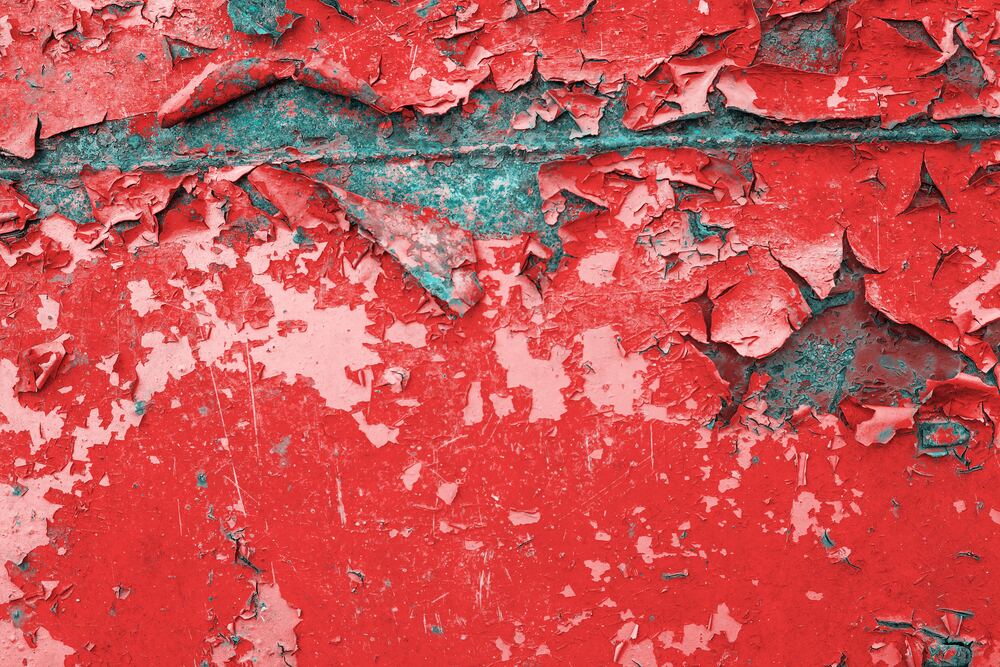 Flaking red lead-based paint on a metal surface