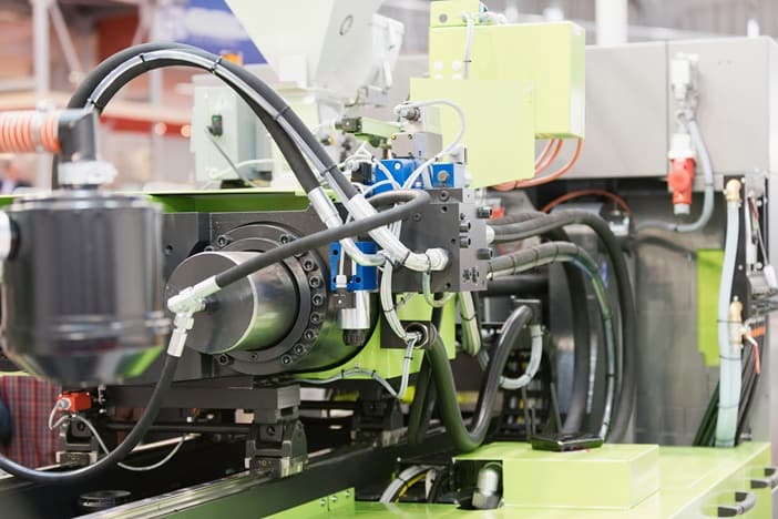 Industrial plastic injection-moulding machine on a factory floor — plastic fume and vapour source