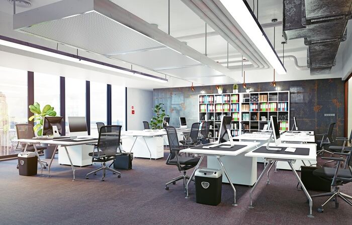 Open-plan office workspace with desks and ventilation ducts overhead — occupant wellbeing focus